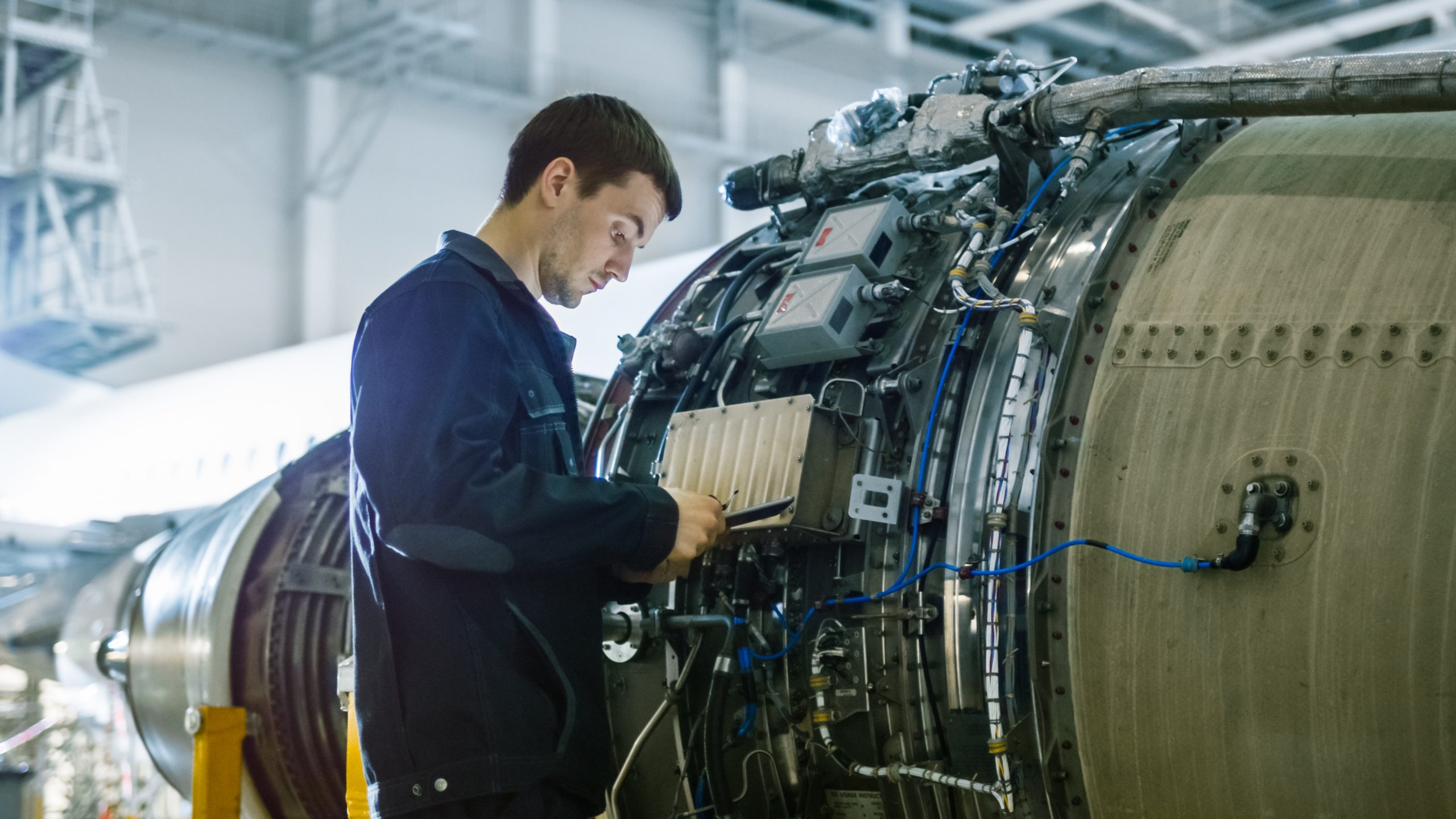 aircraft maintenance mechanic inspecting and working on airplane jet engine in hangar